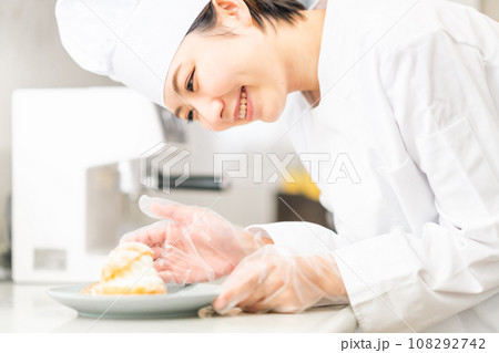 シュークリームをお皿に盛り付けるパティシエ 108292742