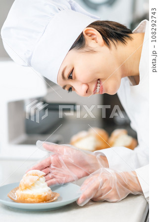シュークリームをお皿に盛り付けるパティシエ 108292743