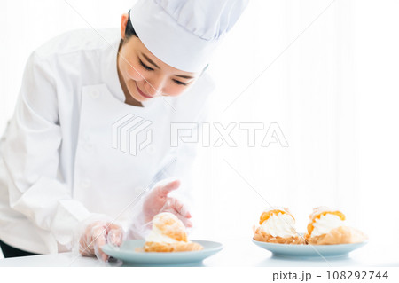 シュークリームをお皿に盛り付けるパティシエ 108292744