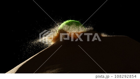 Tennis ball throw hit sand soil and Deep impact on sand hill and splash all over area. Tennis ball hit Sand dune hill over wind storm and blast dust splash over mountain. Black background isolated 108292854