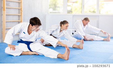 Teacher and followers perform warm-up exercises and legs stretching Teacher and followers perform warm-up exercises and legs stretching 108293671