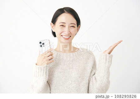 スマートフォンを持って手のひらで右側を指す女性　白背景 108293826