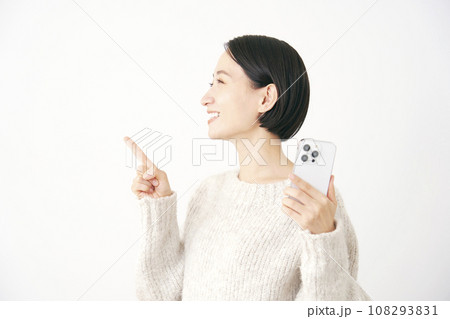 スマートフォンを持って左側を指差す女性　白背景 108293831