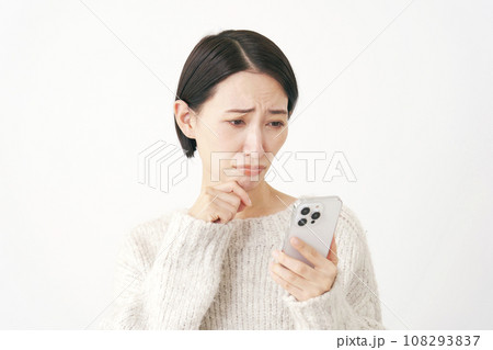 スマートフォンを持って困る女性　白背景 108293837
