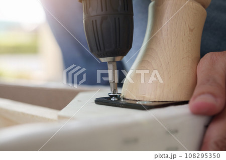 man assembling sofa furniture at home using cordless screwdriver man assembling sofa furniture at home using cordless screwdriver 108295350