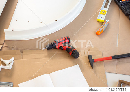 Cordless screwdriver and tool on cardboard paper assembly furniture concept Cordless screwdriver and tool on cardboard paper assembly furniture concept 108296551