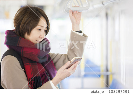 電車でスマホを見る冬服を着たミドル女性 108297591