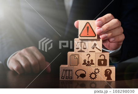 コンプライアンス違反について弁護士が警告するイメージ。テーブルに木のブロックを積み上げる男性。警告マ コンプライアンス違反について弁護士が警告するイメージ。テーブルに木のブロックを積み上げる男性。警告マ 108298030