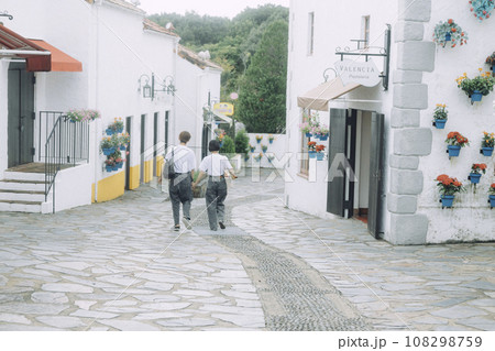 志摩スペイン村　ペアルックで手をつなぐカップルの後ろ姿 108298759