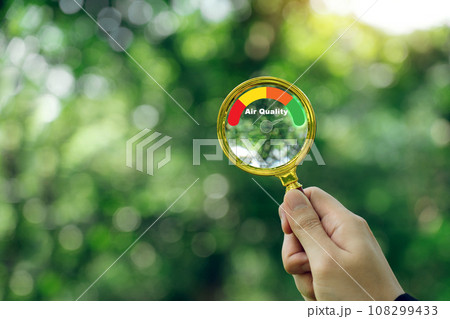 Hand holding a magnifying glass to check the good air quality and clean outdoor air quality safe. Hand holding a magnifying glass to check the good air quality and clean outdoor air quality safe. 108299433