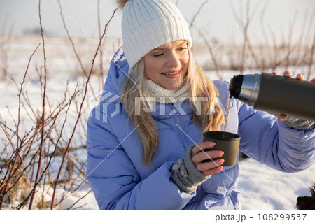 Drinking warming tea from a thermos during a winter hike. 108299537