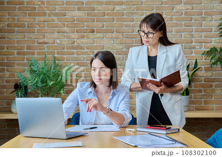 Two businesswomen talking and discussing in office 108302100