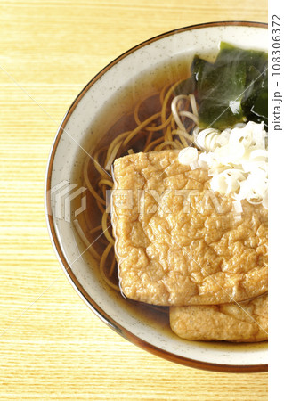 油揚げ2枚とワカメと葱が乗った熱々のきつね蕎麦を俯瞰で撮影 油揚げ2枚とワカメと葱が乗った熱々のきつね蕎麦を俯瞰で撮影 108306372