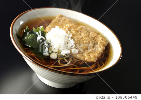 油揚げ2枚とワカメと葱が乗った熱々のきつね蕎麦を黒背景で撮影 108306449