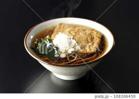 油揚げ2枚とワカメと葱が乗った熱々のきつね蕎麦を黒背景で撮影 油揚げ2枚とワカメと葱が乗った熱々のきつね蕎麦を黒背景で撮影 108306450