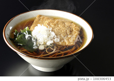 油揚げ2枚とワカメと葱が乗った熱々のきつね蕎麦を黒背景で撮影 油揚げ2枚とワカメと葱が乗った熱々のきつね蕎麦を黒背景で撮影 108306453