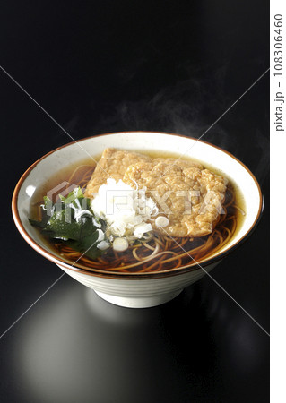 油揚げ2枚とワカメと葱が乗った熱々のきつね蕎麦を黒背景で撮影 油揚げ2枚とワカメと葱が乗った熱々のきつね蕎麦を黒背景で撮影 108306460