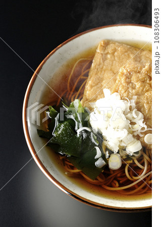 油揚げ2枚とワカメと葱が乗った熱々のきつね蕎麦を黒背景で俯瞰撮影 油揚げ2枚とワカメと葱が乗った熱々のきつね蕎麦を黒背景で俯瞰撮影 108306493