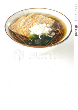 油揚げ2枚とワカメと葱が乗った熱々のきつね蕎麦を白背景で撮影 108306559