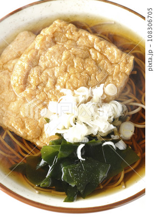 油揚げ2枚とワカメと葱が乗った熱々のきつね蕎麦を白背景で俯瞰撮影 108306705