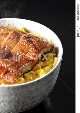 錦糸玉子と鰻の蒲焼きの熱々丼ぶりを黒背景で撮影 108306998