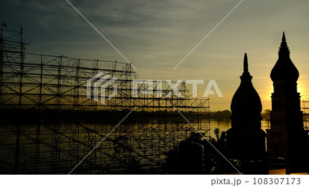 The sun is rising on the riverside in front of a Thai temple. 108307173