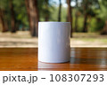 A white mug placed on a log with a view of nature in the background. 108307293