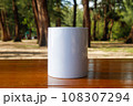 A white mug placed on a log with a view of nature in the background. 108307294