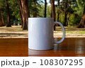 A white mug placed on a log with a view of nature in the background. 108307295