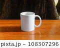 A white mug placed on a log with a view of nature in the background. 108307296