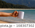 A white mug placed on a log with a view of nature in the background. 108307302