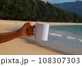 A white mug placed on a log with a view of nature in the background. 108307303