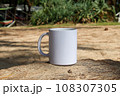 A white mug placed on a log with a view of nature in the background. 108307305