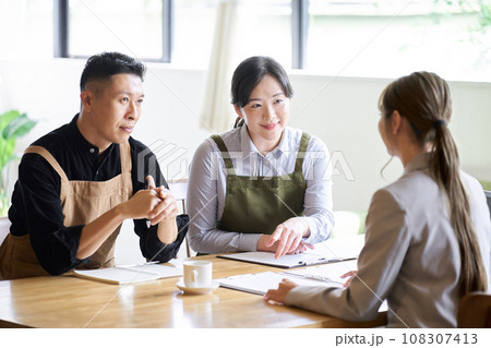 ビジネスウーマンのプレゼンを聞く飲食店の経営者 108307413