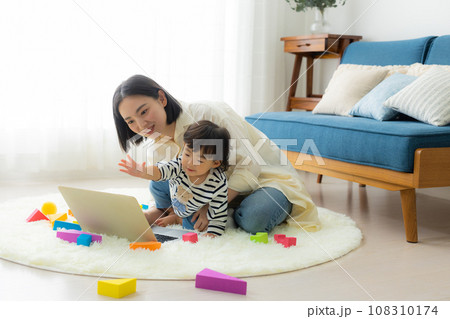子供を抱っこしながらパソコンを見るお母さん 子供を抱っこしながらパソコンを見るお母さん 108310174