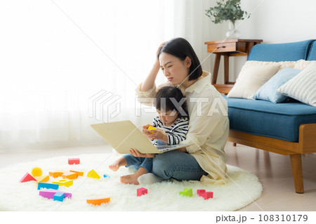 子供を抱っこしながらパソコンを見るお母さん 子供を抱っこしながらパソコンを見るお母さん 108310179