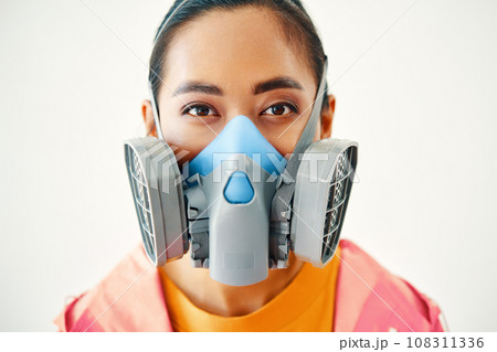 Close up portrait of young woman in protective respirator mask looking to camera over white background Close up portrait of young woman in protective respirator mask looking to camera over white background 108311336