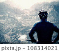 Teenager boy sit on mountain bike and watching from Alps peak down. Dolomite Alps, 108314021