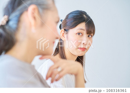 シニア女性の隣で、ストレスを感じる若い女性 108316361