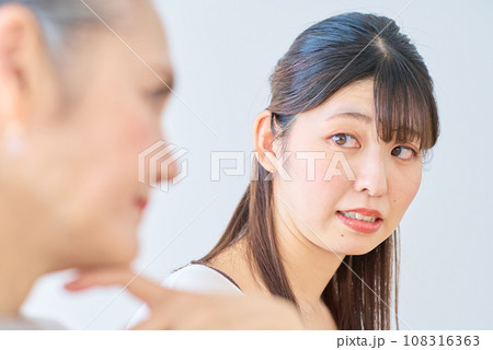 シニア女性の隣で、ストレスを感じる若い女性 シニア女性の隣で、ストレスを感じる若い女性 108316363
