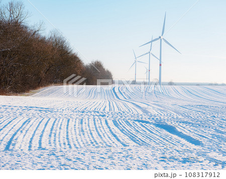 Wind turbines and agricultural field on winter day. 108317912