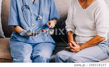 Doctor and patient sitting and talking at medical examination at hospital office, close-up. Therapist filling up medication history records. Medicine and healthcare concept. 108318137