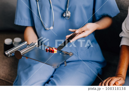 Doctor and patient sitting and talking at medical examination at hospital office, close-up. Therapist filling up medication history records. Medicine and healthcare concept. 108318138