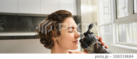 Young strong sporty athletic fitness trainer, instructor woman wearing brown tracksuit sitting on yoga mat drink water training do exercises at home gym indoor. Workout sport motivation concept 108319684