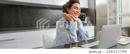 Working woman using laptop at home, doing her taxes paperwork, watching online course in kitchen Working woman using laptop at home, doing her taxes paperwork, watching online course in kitchen 108321794
