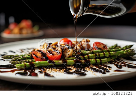 drizzling balsamic glaze over a dish of asparagus and scrambled quail eggs 108321823