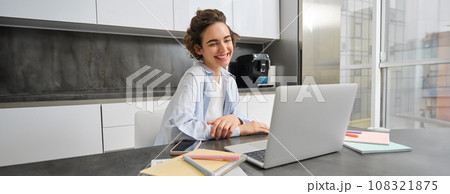 Portrait of smiling young woman connects to online webinar, studies at home on remote, looking at laptop with happy face, teacher people via tutor website Portrait of smiling young woman connects to online webinar, studies at home on remote, looking at laptop with happy face, teacher people via tutor website 108321875