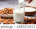a hand drizzling almond milk over sliced almonds 108321911