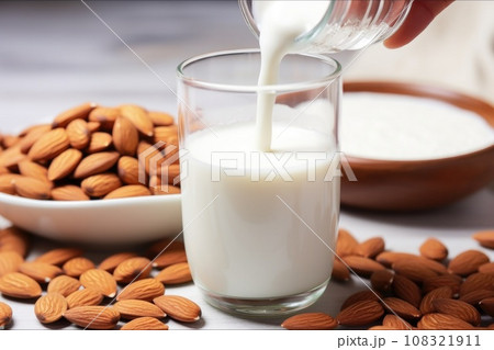 a hand drizzling almond milk over sliced almonds 108321911