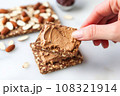 hand holding spatula to serve almond butter whole grain toast 108321914